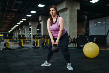 Overweight woman, exercise with kettlebell in gym