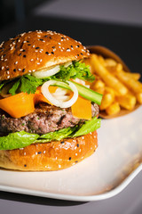 Healthy homemade beef burger with veggies. Potato fries on the side. Perfect concept for burger place and delivery promotion. Food photography focus view.