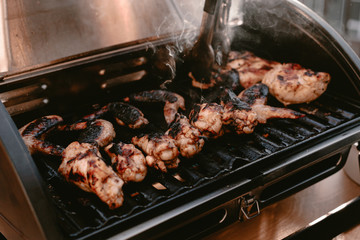 Grill season outdoor in park or balcony. Spring summer grilling. Balcony gas grill. Barbeque fourth of July weekend. Chicken wings on grill. Flame and smoke over grill. BBQ quarantine on balcony.