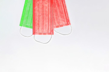 on top are 3 medical masks of green and red colors on a light background. masks are collected in...