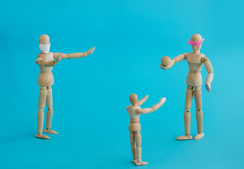 Concept - ban on ball games with children during quarantine. Group of wooden little men mannequins. A man in a protective medical mask prohibits others from playing actively. Social distance.