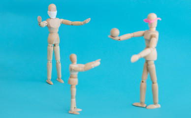 Concept - ban on ball games with children during quarantine. Group of wooden little men mannequins. A man in a protective medical mask prohibits others from playing actively. Social distance.