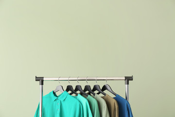 Rack with modern clothes on color background