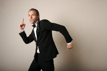 Cool young man in full tuxedo dancing with silly gestures