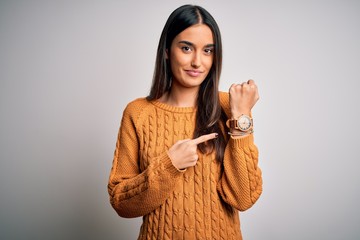Young beautiful brunette woman wearing casual sweater over isolated white background In hurry...