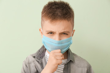 Ill little boy wearing protective mask on color background. Concept of epidemic