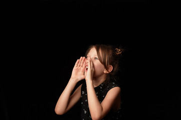 The girl is 6 years old, screaming,hands at the face in the form of a mouthpiece. To shout.A girl...