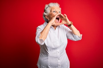 Senior beautiful woman wearing elegant shirt standing over isolated red background Shouting angry...