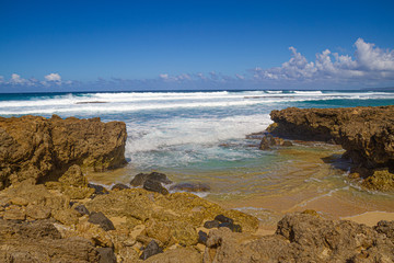 The clear blue waters of the Pacific Ocean splashing onto the rocky shoreline of Oahu in the Hawaiian Islands.