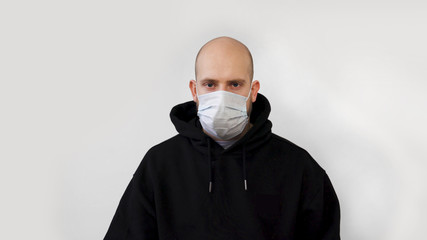  A man with a beard coughs and puts on a medical mask isolated