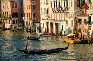 Fototapeta na wymiar Venetian gondolier on a gondola through green canal waters of Venice Italy