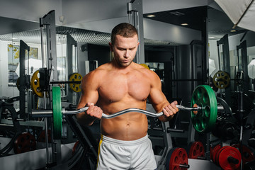 Obraz premium A young athletic guy is engaged in fitness in the gym. Fitness, bodybuilding