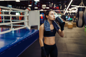 Woman in boxing bandages drinks water, box