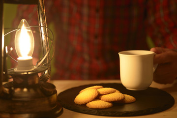 ランタンの灯りでコーヒーを飲む男性