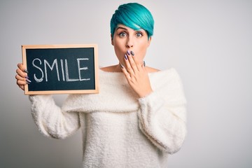 Young woman with blue fashion hair holding blackboard with smile message cover mouth with hand...