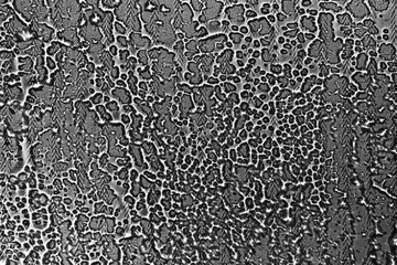 View on a black-white background with the texture of flowing drops of water on glass through a transparent fabric. Concept background, texture.