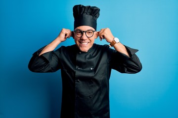 Middle age handsome grey-haired chef man wearing cooker uniform and hat Smiling pulling ears with fingers, funny gesture. Audition problem