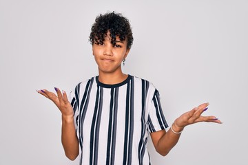 Beautiful african american afro woman wearing casual striped t-shirt over white background clueless...