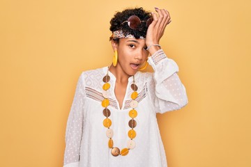 Young beautiful african american afro hippie woman wearing sunglasses and accessories surprised...