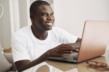 A man of African appearance at home in front of a laptop