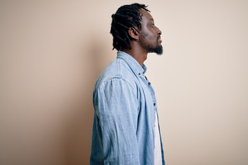 Young handsome african american man wearing casual denim shirt over white background looking to side, relax profile pose with natural face with confident smile.