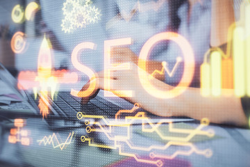 Double exposure of woman hands working on computer and seo hologram drawing. internet search...
