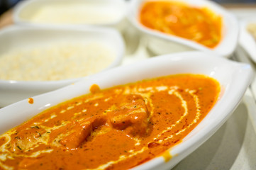 Bowl of Indian curry with rice in the background