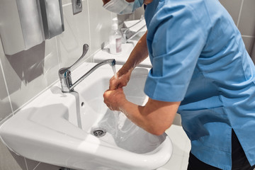 Close-up of a doctor washing his hands using a disinfectant dispenser.