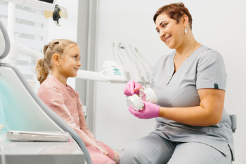 Child girl having dental check up by woman specialist in dentist office