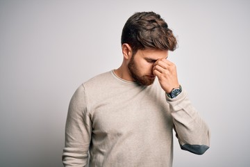 Young handsome blond man with beard and blue eyes wearing casual sweater tired rubbing nose and eyes feeling fatigue and headache. Stress and frustration concept.