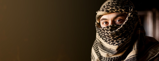 Portrait of arab man in keffiyeh on face. with a sad face in a military jacket and a headdress from...