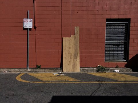 Wooden Planks Leaning Against Brick Wall In Empty Back Alley