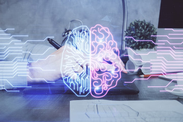 Double exposure of man's hand holding and using a digital device and brain hologram drawing. Data...