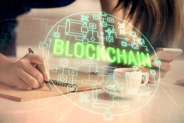 Double exposure of blockchain business sketch hologram and woman holding and using a mobile device.