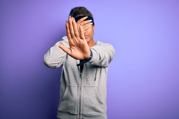 Young african american sportswoman doing sport wearing sportswear over purple background covering eyes with hands and doing stop gesture with sad and fear expression. Embarrassed and negative concept.