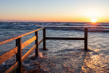 Fototapeta premium sunset at Sauble Beach in early April. High water up to the fence.