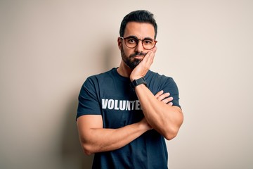 Handsome man with beard wearing t-shirt with volunteer message over white background thinking...