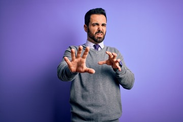 Handsome businessman with beard wearing casual tie standing over purple background disgusted expression, displeased and fearful doing disgust face because aversion reaction. With hands raised