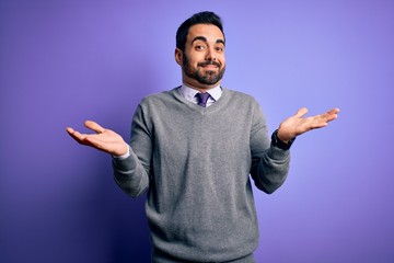 Naklejka premium Handsome businessman with beard wearing casual tie standing over purple background clueless and confused expression with arms and hands raised. Doubt concept.