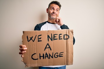 Young handsome activist man holding banner with change message over pink background serious face thinking about question, very confused idea