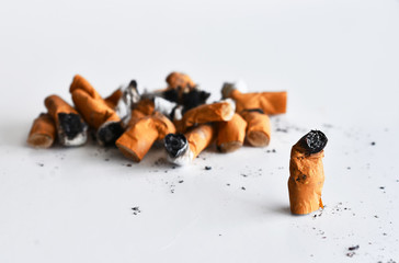 A close up image of several dirty old cigarette butts in a pile. 