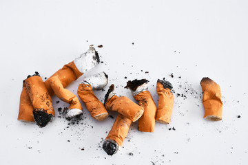 A close up image of several dirty old cigarette butts in a pile. 
