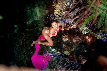 Beautiful teenage girl in a cenote from the Mayan Riviera in cloth.