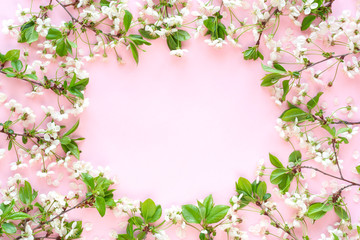 Fototapeta na wymiar Round frame made of blooming cherry branches on pastel pink background. Happy Mother's Day, Birthday or other holiday greeting card. Floral spring background. Flat lay, top view, copy space.