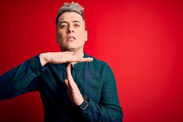 Young handsome modern man wearing elegant green shirt over red isolated background Doing time out...