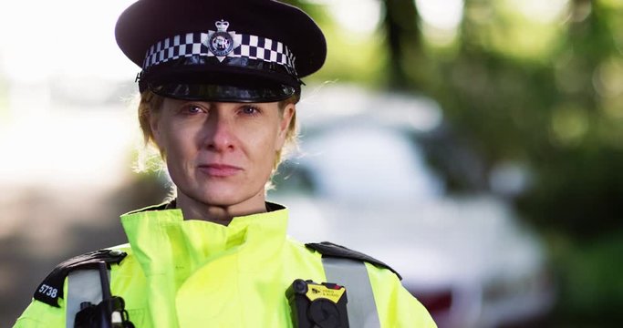 4K Close up portrait of policewoman with serious expression breaking into a smile. Slow motion.