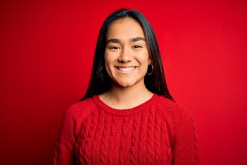 Fototapeta premium Young beautiful asian woman wearing casual sweater standing over isolated red background with a happy and cool smile on face. Lucky person.