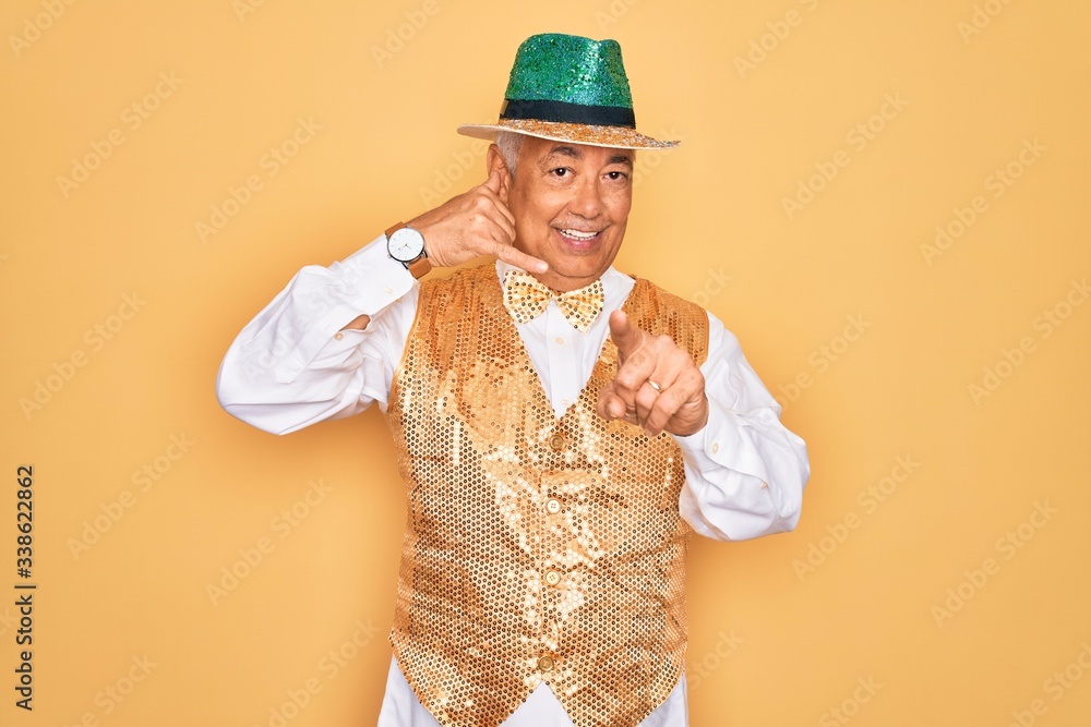 Canvas Prints Middle age senior grey-haired man wearing Brazilian carnival custome over yellow background smiling doing talking on the telephone gesture and pointing to you. Call me.