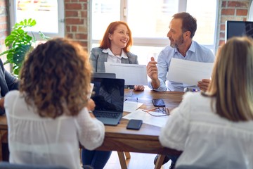 Group of business workers working together. Sitting on desk using laptop reading documents at the office