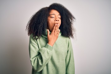 Young beautiful african american woman with afro hair wearing green winter sweater bored yawning tired covering mouth with hand. Restless and sleepiness.